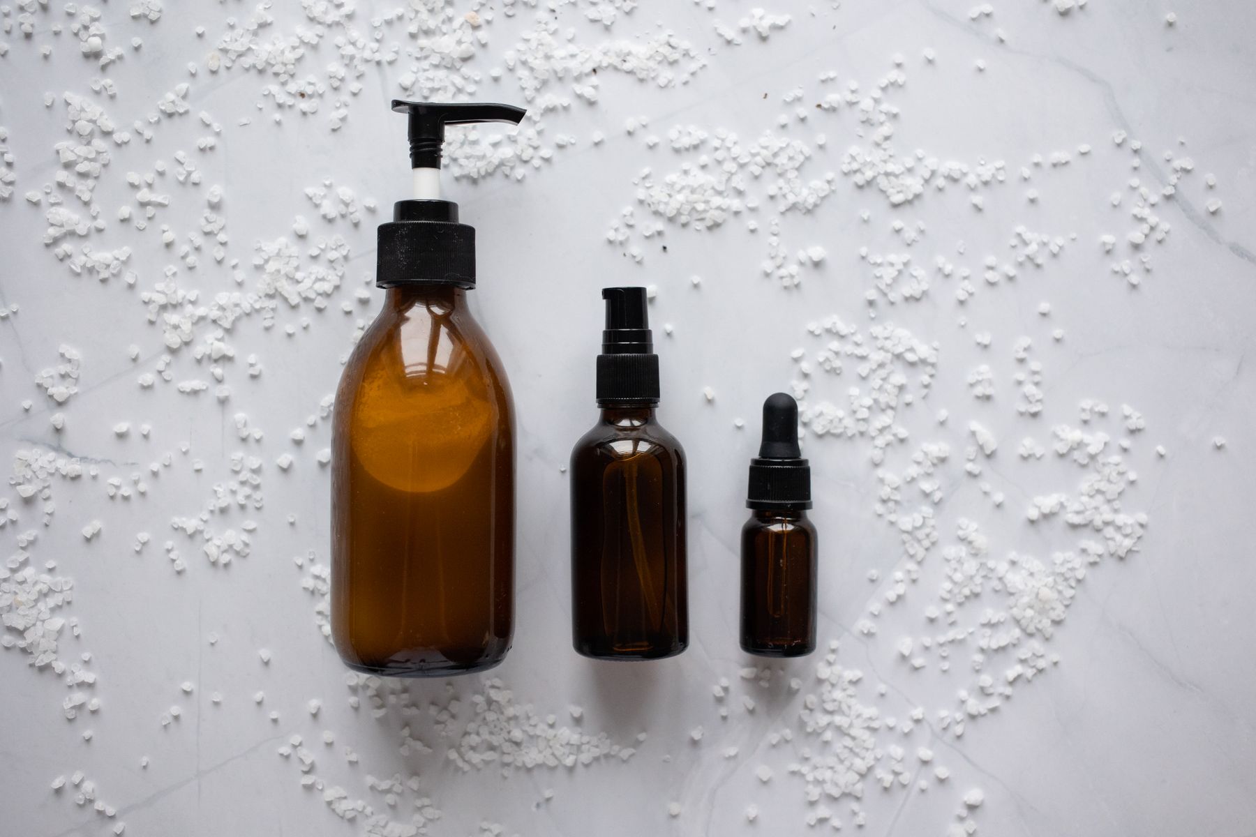 Amber skincare bottles on a pale stone surface